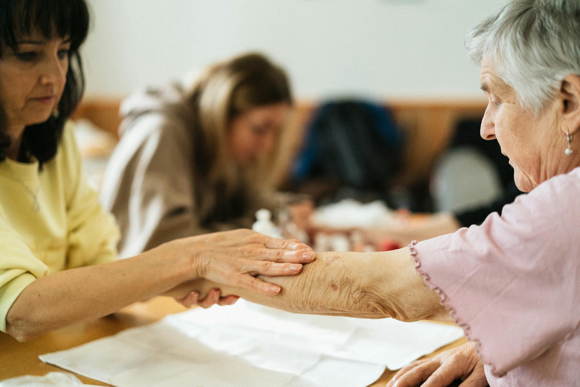 Pflegerin hält die Hand einer Seniorin im vertrauten Gespräch
